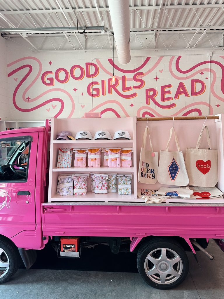 Small hot pink book truck "Litlte Miss Smuttie" parked inside Good Girl Books